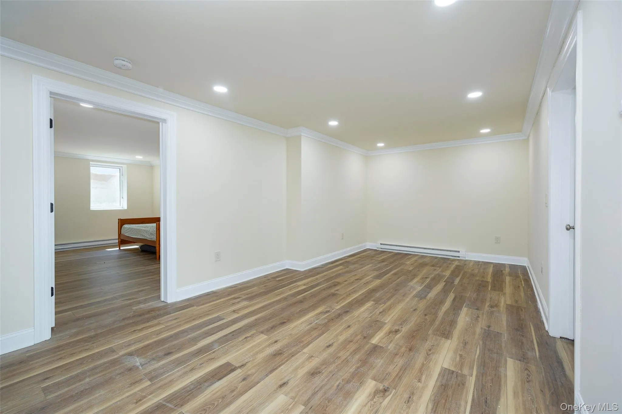 Spare room with light wood-style flooring, recessed lighting, crown molding, and a baseboard heating unit Spare room with light wood-style flooring, recessed lighting, crown molding, and a baseboard heating unit