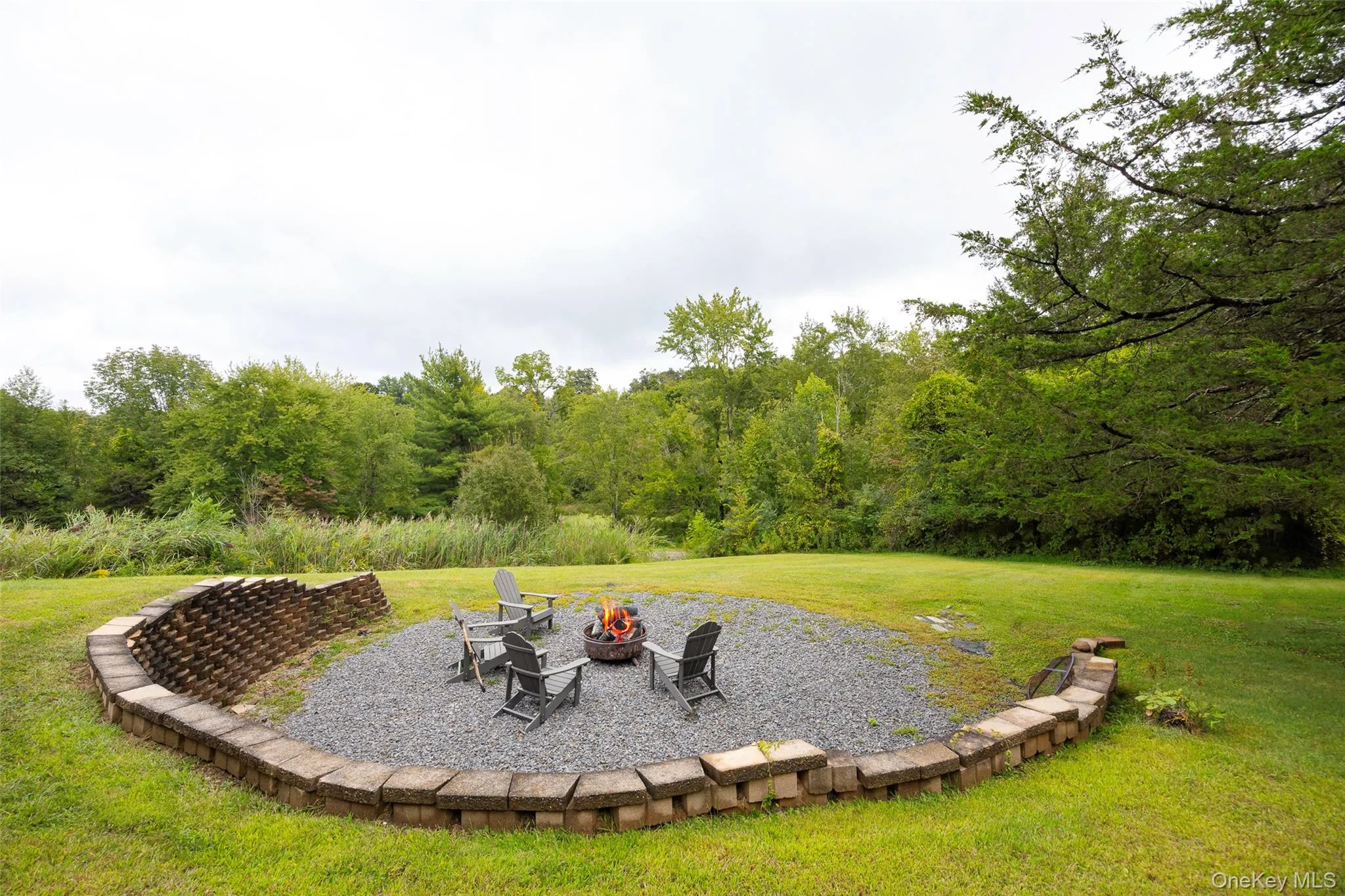 View of green lawn with an outdoor fire pit and a patio area View of green lawn with an outdoor fire pit and a patio area