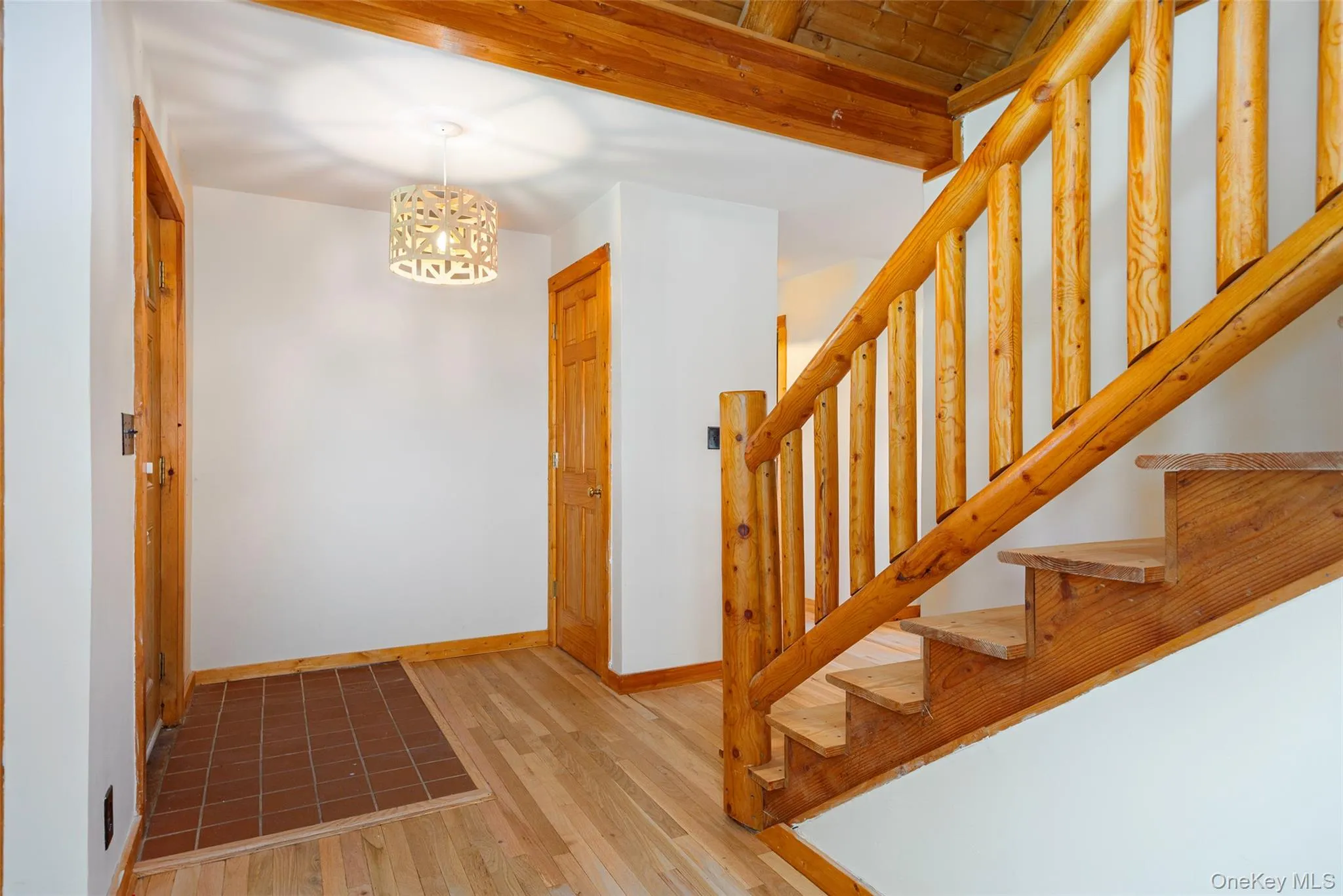 Stairway featuring a chandelier, wood-type flooring, and beam ceiling Stairway featuring a chandelier, wood-type flooring, and beam ceiling