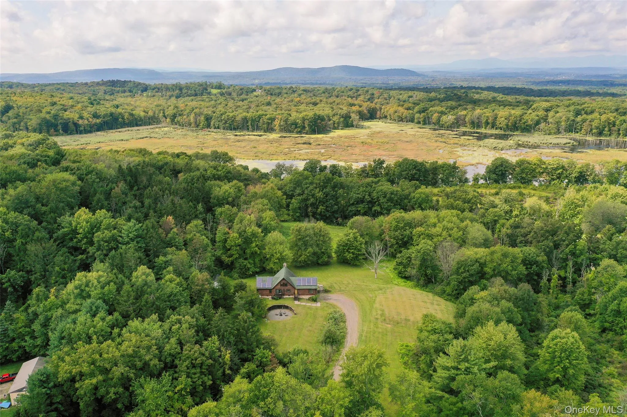 Aerial view of property and surrounding area featuring a heavily wooded area and a mountain backdrop Aerial view of property and surrounding area featuring a heavily wooded area and a mountain backdrop
