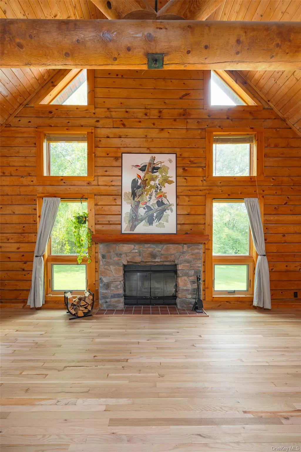 Unfurnished living room featuring a stone fireplace, hardwood / wood-style flooring, a wooden ceiling with exposed beams, and high vaulted ceiling Unfurnished living room featuring a stone fireplace, hardwood / wood-style flooring, a wooden ceiling with exposed beams, and high vaulted ceiling