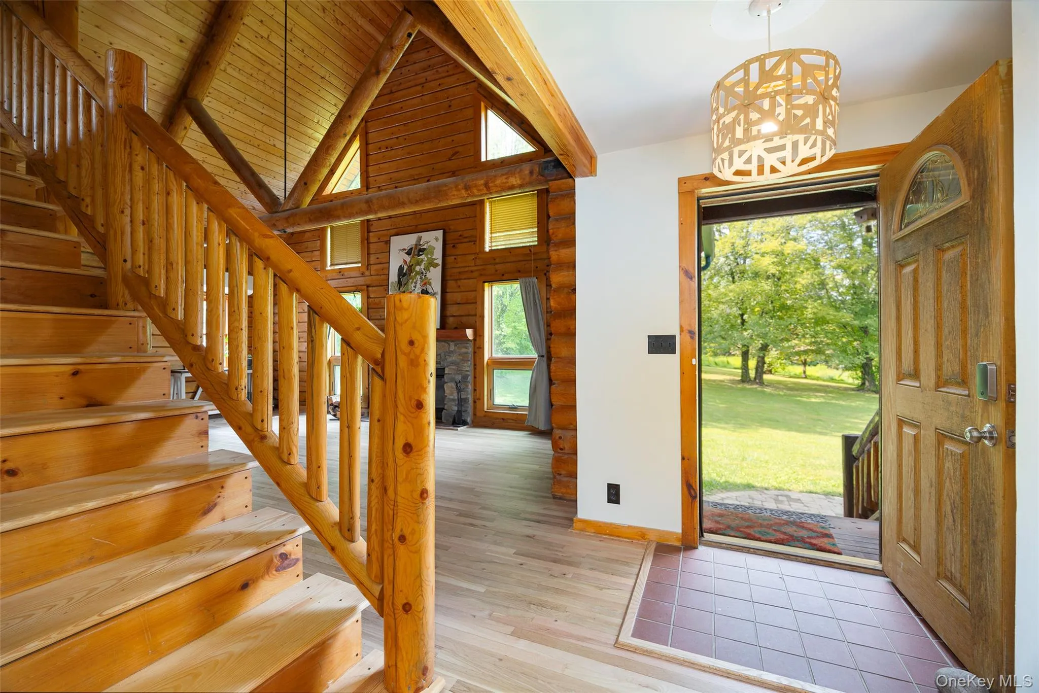 Entryway with light wood-style floors, stairs, a chandelier, and log walls Entryway with light wood-style floors, stairs, a chandelier, and log walls