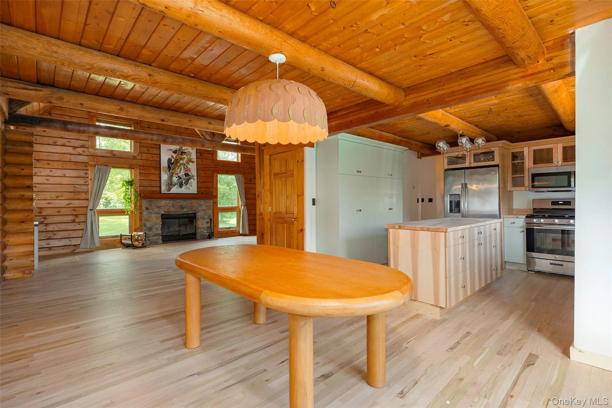 Kitchen featuring glass insert cabinets, light wood-type flooring, appliances with stainless steel finishes, pendant lighting, and light countertops Kitchen featuring glass insert cabinets, light wood-type flooring, appliances with stainless steel finishes, pendant lighting, and light countertops