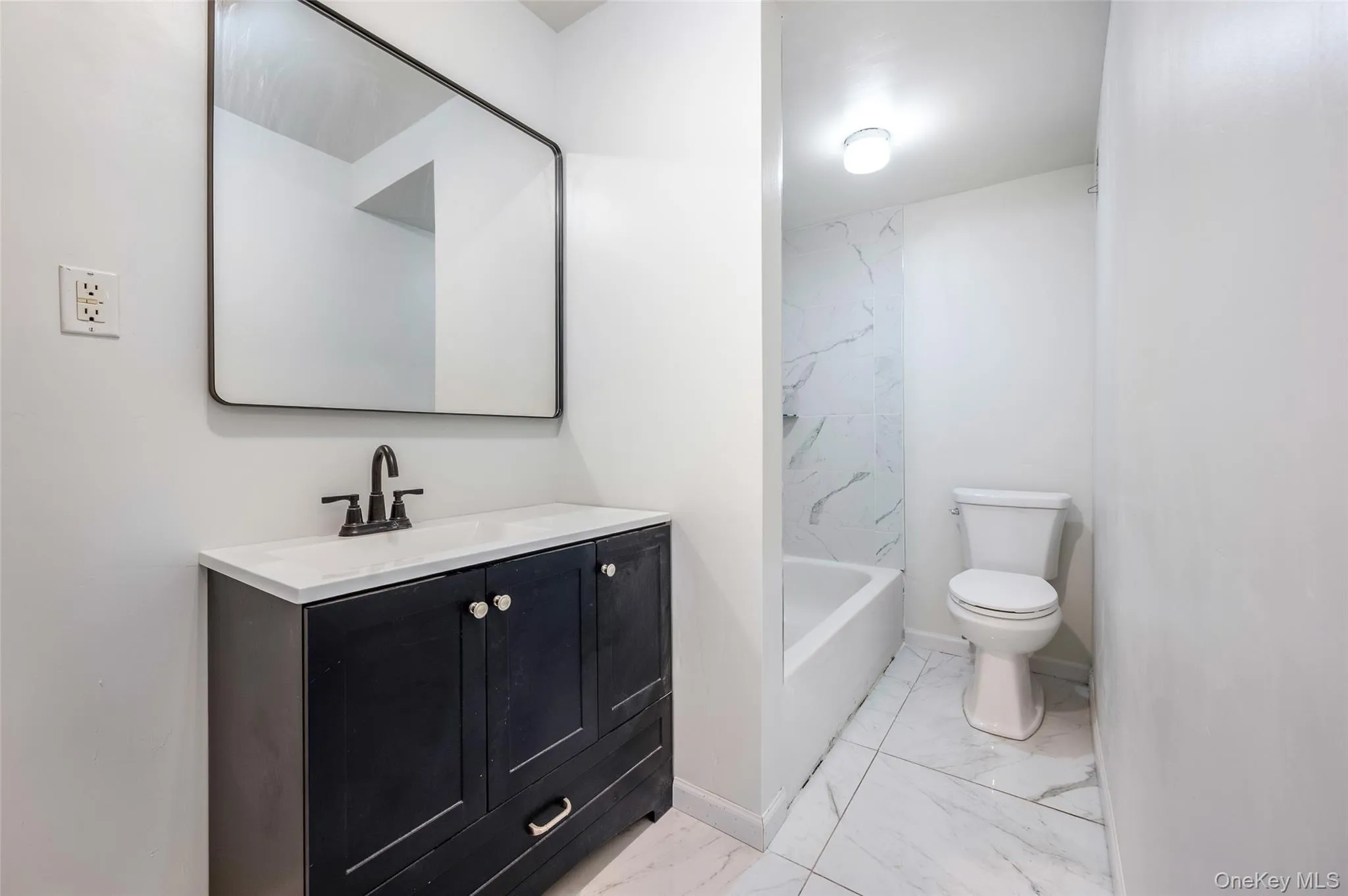 Full bath featuring vanity, light marble finish floors, and washtub / shower combination Full bath featuring vanity, light marble finish floors, and washtub / shower combination