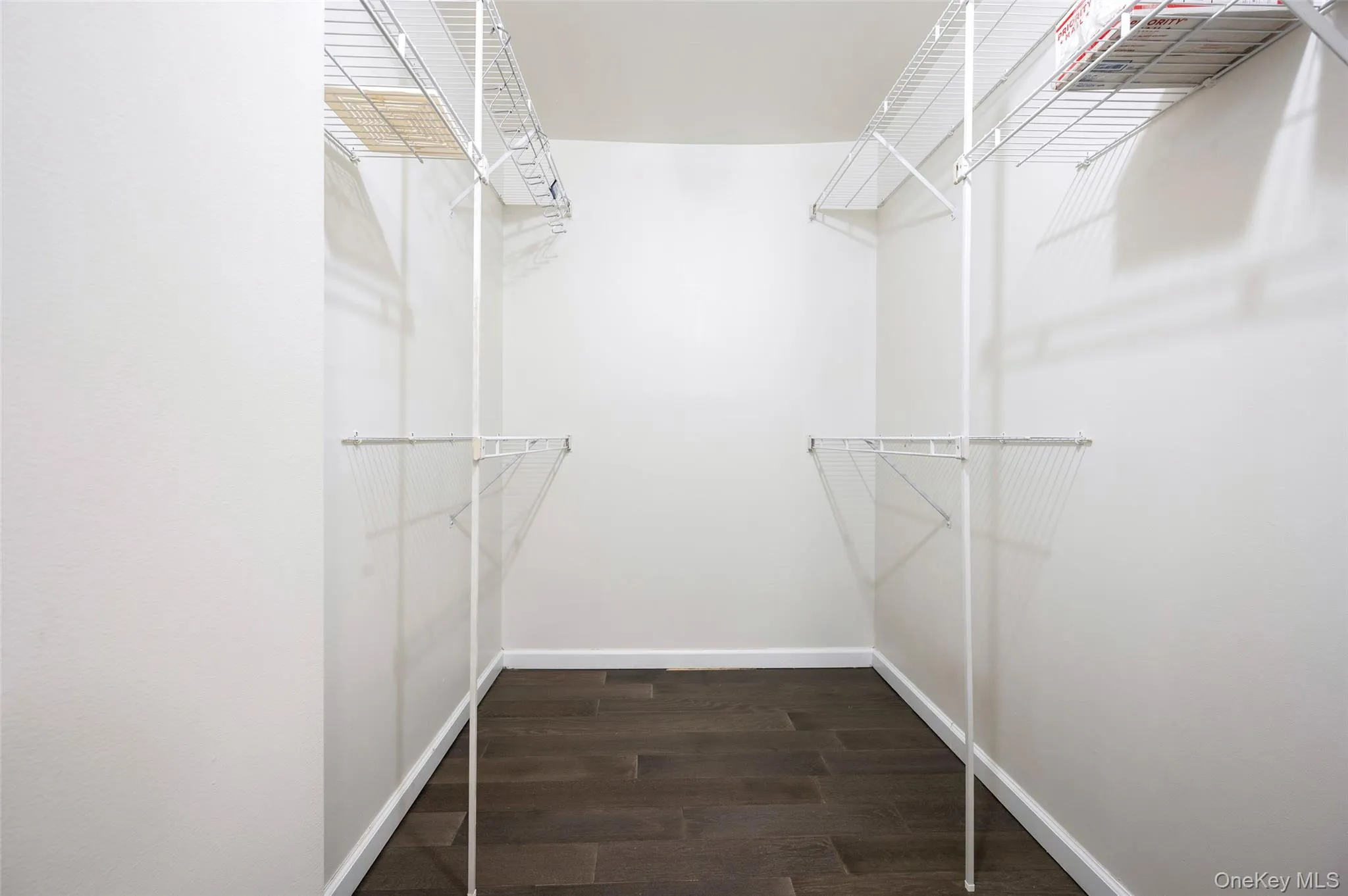 Walk in closet featuring dark wood finished floors Walk in closet featuring dark wood finished floors