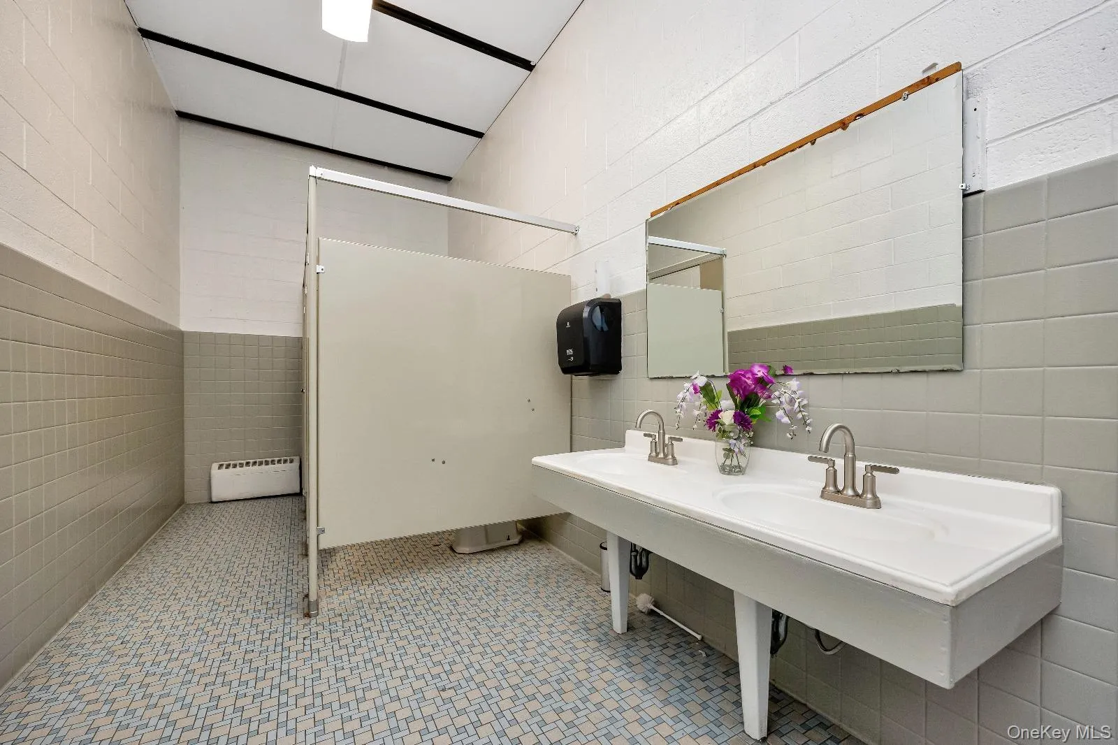 Bathroom with tile walls, double sink, baseboard heating, and a shower Bathroom with tile walls, double sink, baseboard heating, and a shower