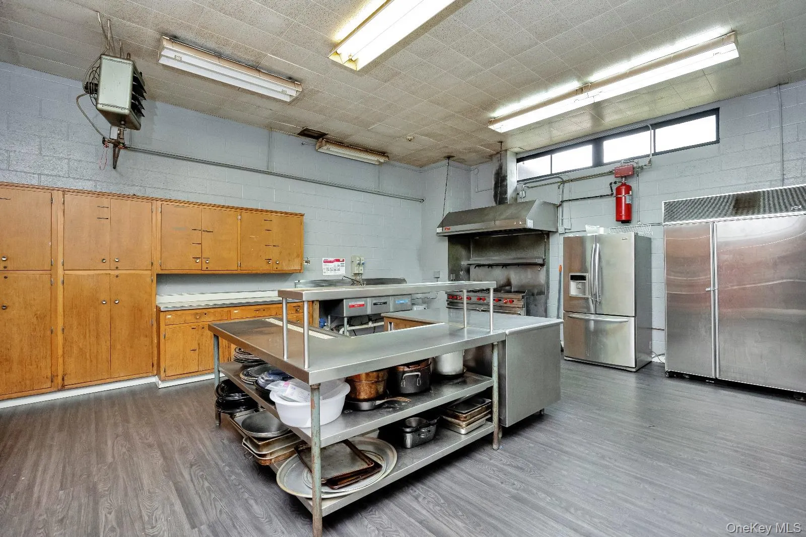 Kitchen with stainless steel counters, stainless steel fridge with ice dispenser, exhaust hood, stainless steel built in refrigerator, and brown cabinetry Kitchen with stainless steel counters, stainless steel fridge with ice dispenser, exhaust hood, stainless steel built in refrigerator, and brown cabinetry
