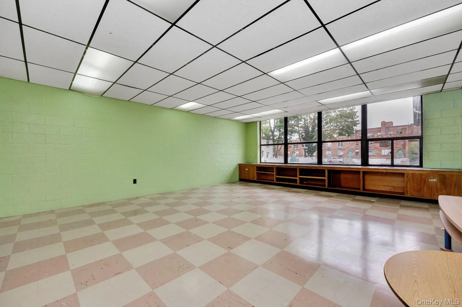 Empty room featuring light floors, concrete block wall, and a drop ceiling Empty room featuring light floors, concrete block wall, and a drop ceiling