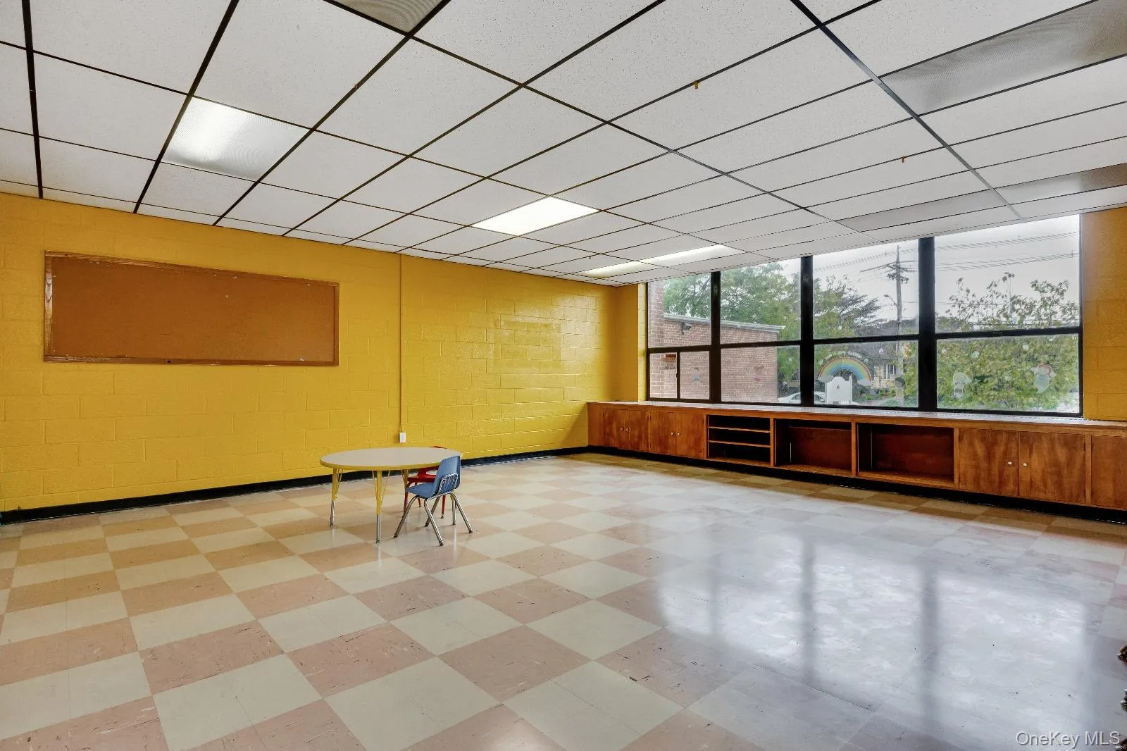 Unfurnished room featuring light floors, a drop ceiling, and concrete block wall Unfurnished room featuring light floors, a drop ceiling, and concrete block wall