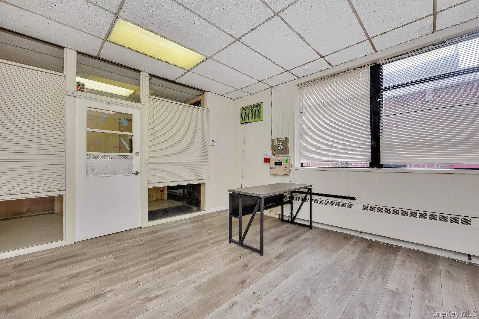 Office space with light wood-style floors, a baseboard radiator, and a paneled ceiling Office space with light wood-style floors, a baseboard radiator, and a paneled ceiling