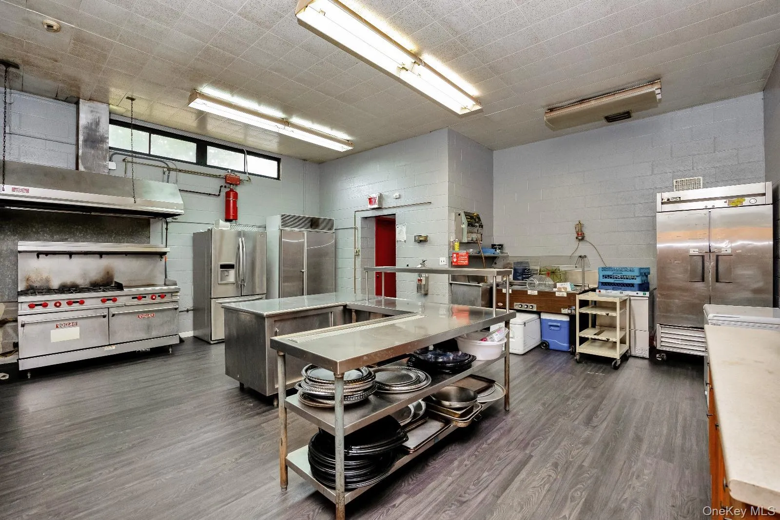 Kitchen featuring high end fridge, stainless steel refrigerator with ice dispenser, exhaust hood, and a kitchen island Kitchen featuring high end fridge, stainless steel refrigerator with ice dispenser, exhaust hood, and a kitchen island