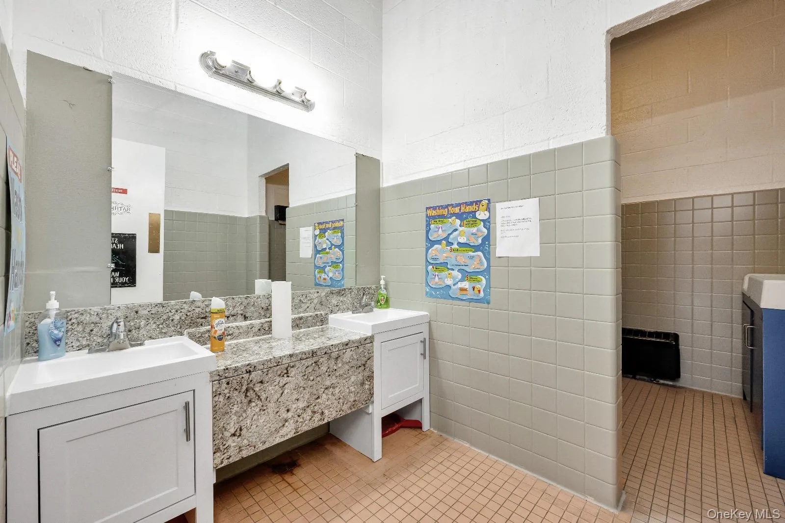 Full bath featuring double vanity, tile walls, and light tile patterned flooring Full bath featuring double vanity, tile walls, and light tile patterned flooring
