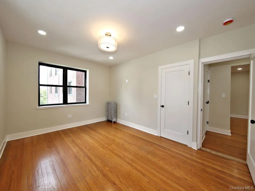 Spare room with recessed lighting, radiator, and light wood finished floors Spare room with recessed lighting, radiator, and light wood finished floors