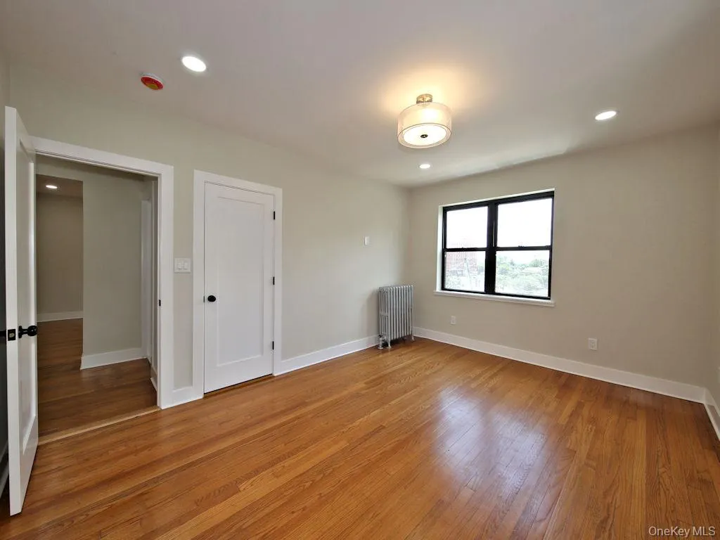 Unfurnished bedroom with recessed lighting, light wood-type flooring, and radiator Unfurnished bedroom with recessed lighting, light wood-type flooring, and radiator