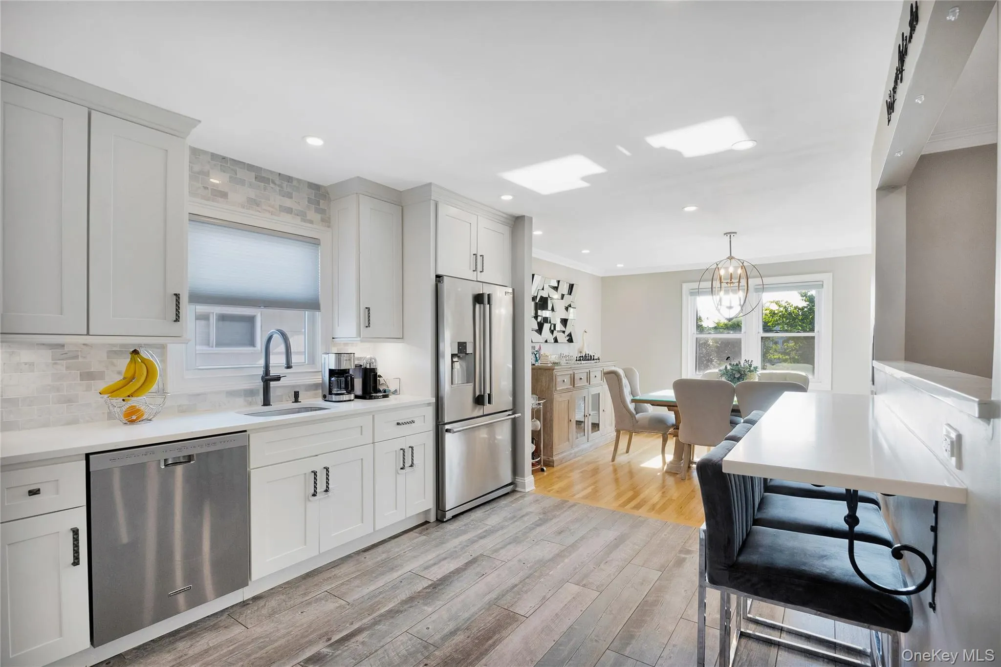 Kitchen featuring stainless steel appliances, light wood-type flooring, decorative light fixtures, decorative backsplash, and recessed lighting Kitchen featuring stainless steel appliances, light wood-type flooring, decorative light fixtures, decorative backsplash, and recessed lighting