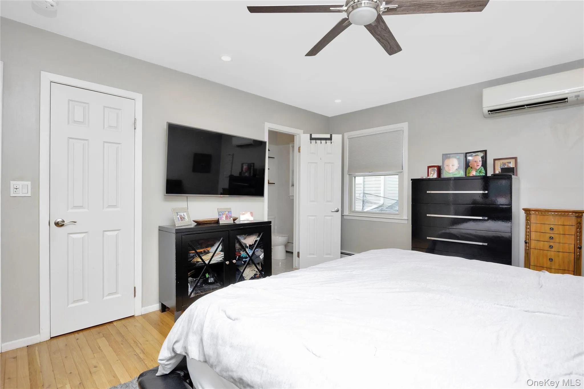 Bedroom featuring a wall mounted air conditioner, light wood-type flooring, recessed lighting, and a ceiling fan Bedroom featuring a wall mounted air conditioner, light wood-type flooring, recessed lighting, and a ceiling fan