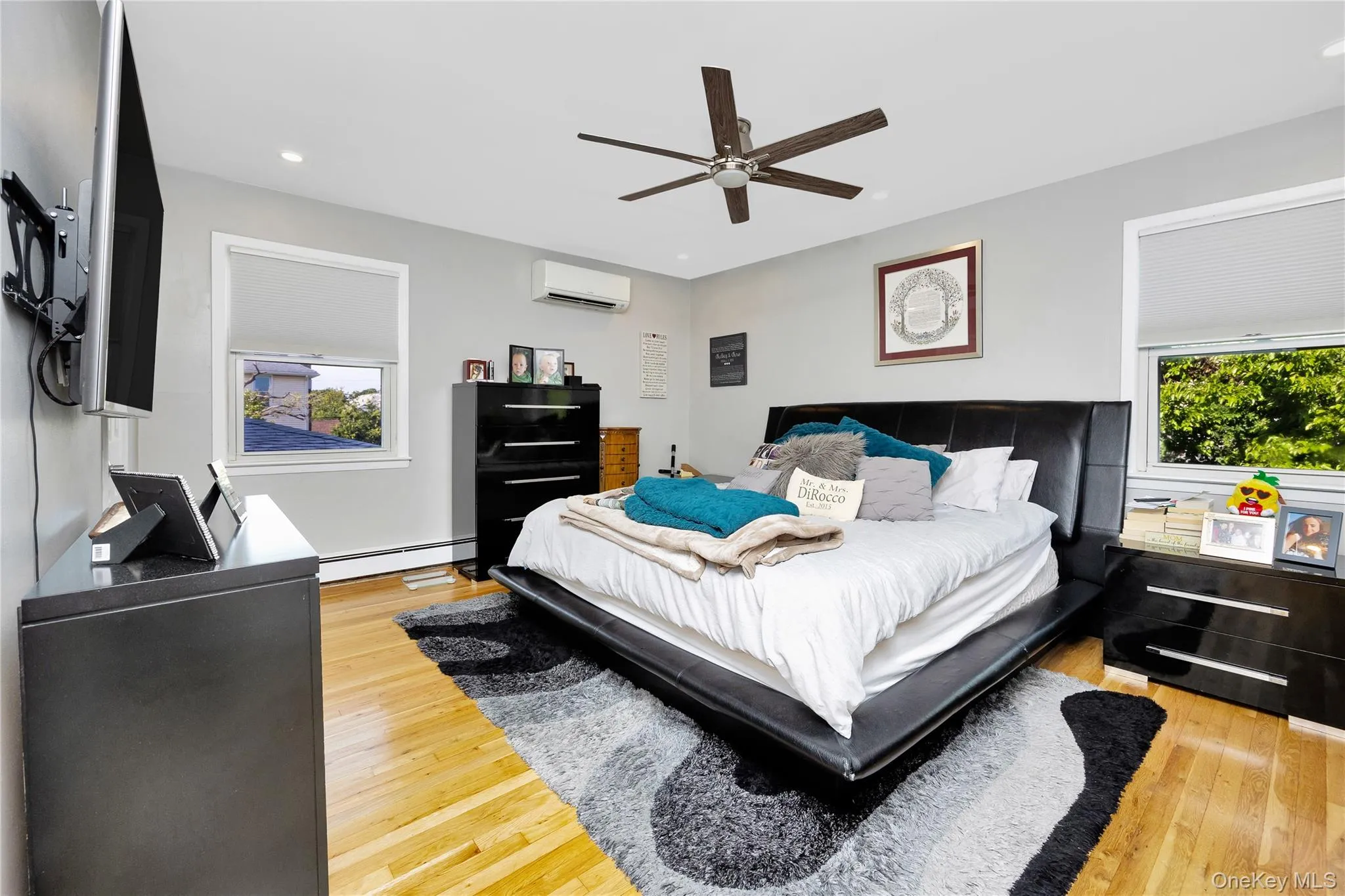 Bedroom featuring light wood finished floors, recessed lighting, a baseboard radiator, a ceiling fan, and a wall mounted AC Bedroom featuring light wood finished floors, recessed lighting, a baseboard radiator, a ceiling fan, and a wall mounted AC