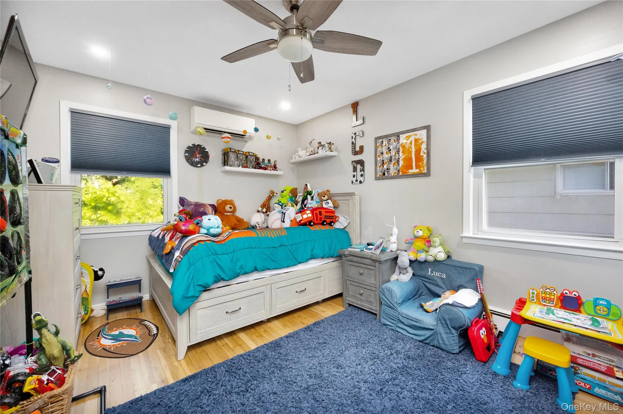 Bedroom with light wood-style floors, a ceiling fan, and a wall mounted air conditioner Bedroom with light wood-style floors, a ceiling fan, and a wall mounted air conditioner