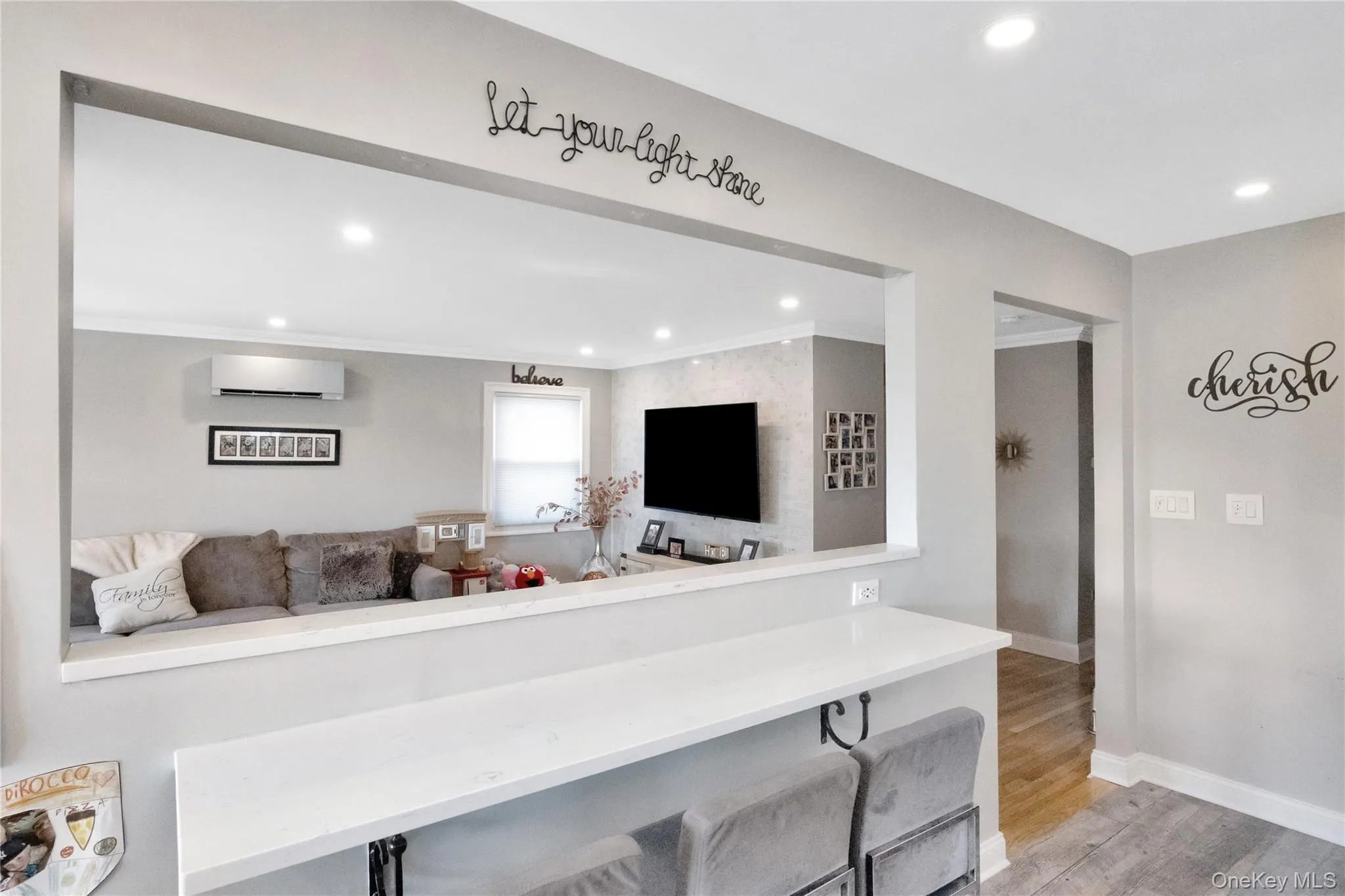 Living area featuring light wood-style floors, recessed lighting, a wall unit AC, and crown molding Living area featuring light wood-style floors, recessed lighting, a wall unit AC, and crown molding
