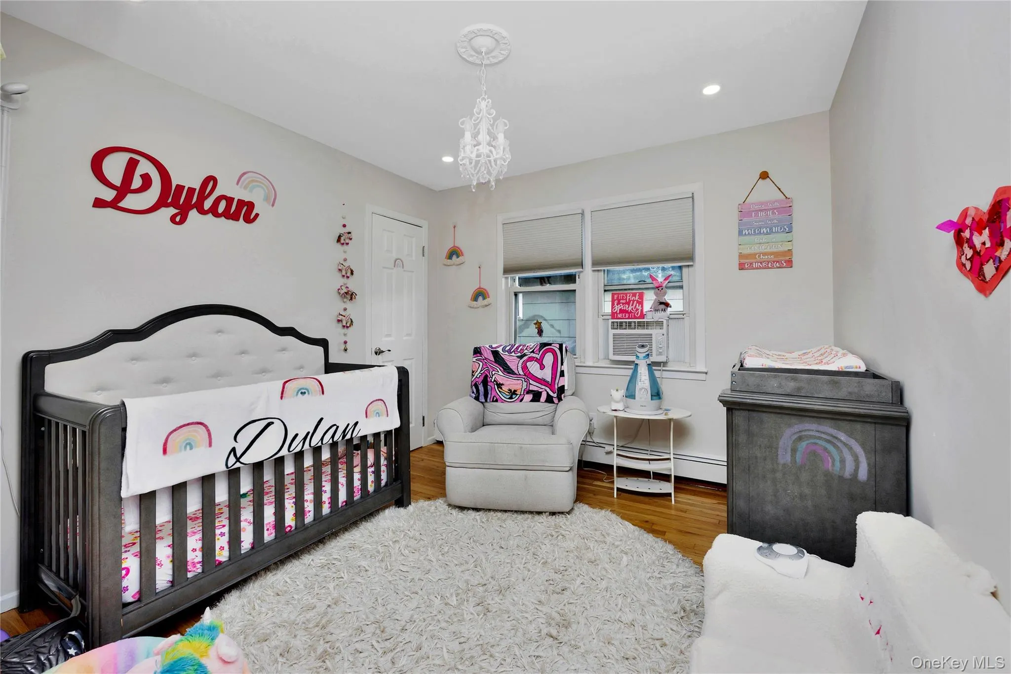 Bedroom with a nursery area, wood finished floors, a chandelier, a baseboard heating unit, and recessed lighting Bedroom with a nursery area, wood finished floors, a chandelier, a baseboard heating unit, and recessed lighting