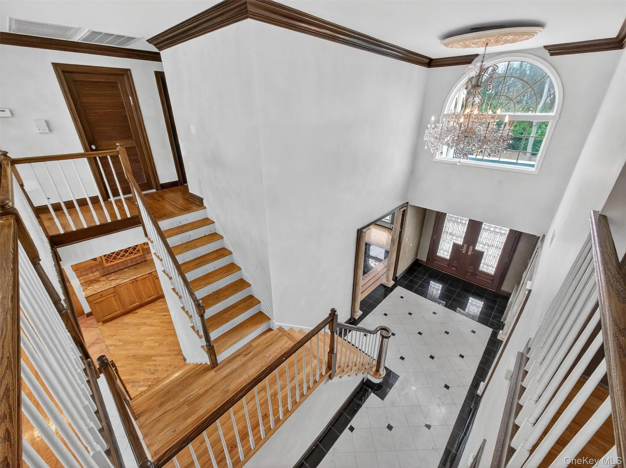 Entryway with a chandelier, crown molding, stairway, light tile patterned floors, and a towering ceiling Entryway with a chandelier, crown molding, stairway, light tile patterned floors, and a towering ceiling
