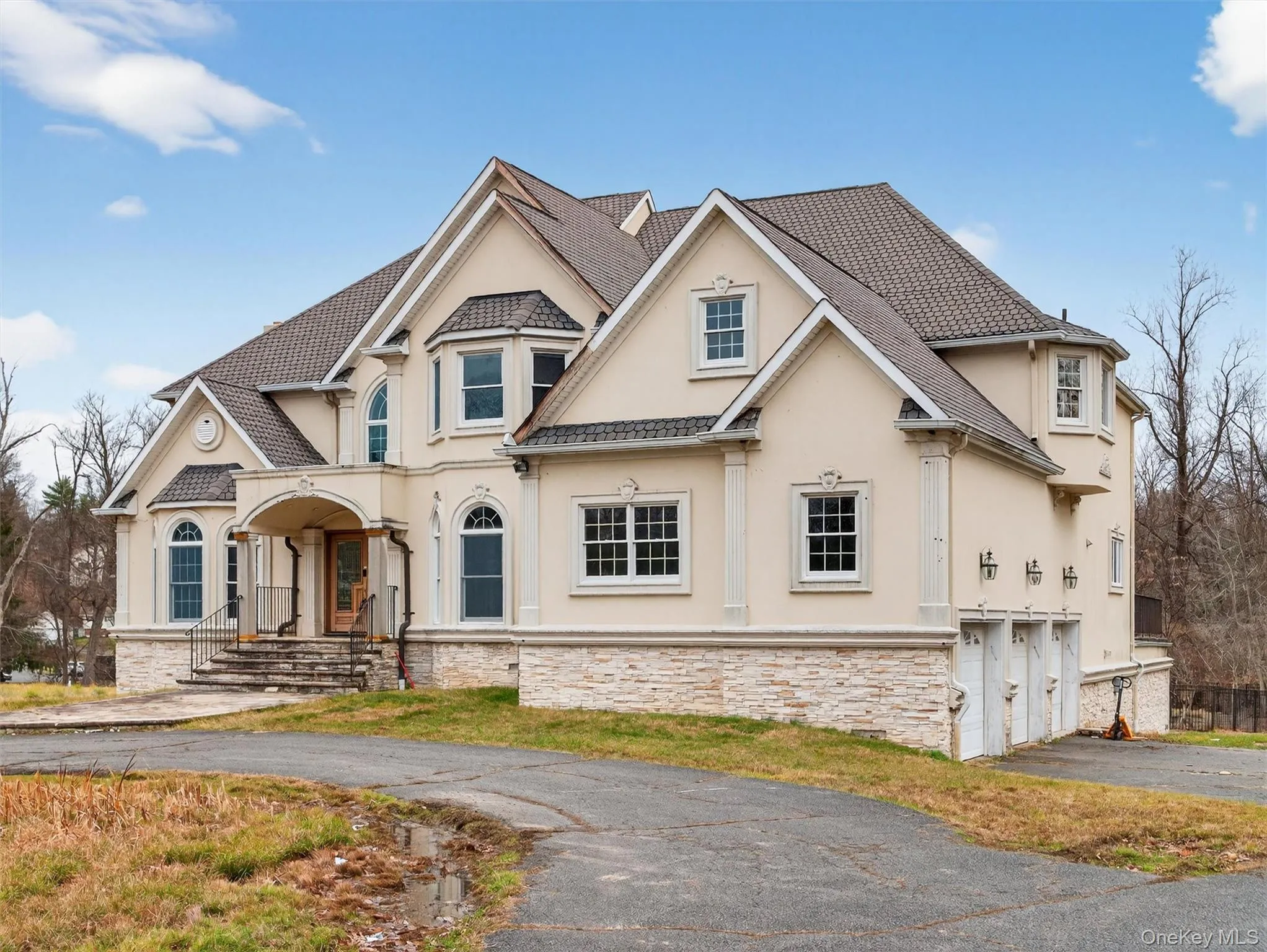 French country inspired facade with driveway, stucco siding, an attached garage, and stone siding French country inspired facade with driveway, stucco siding, an attached garage, and stone siding
