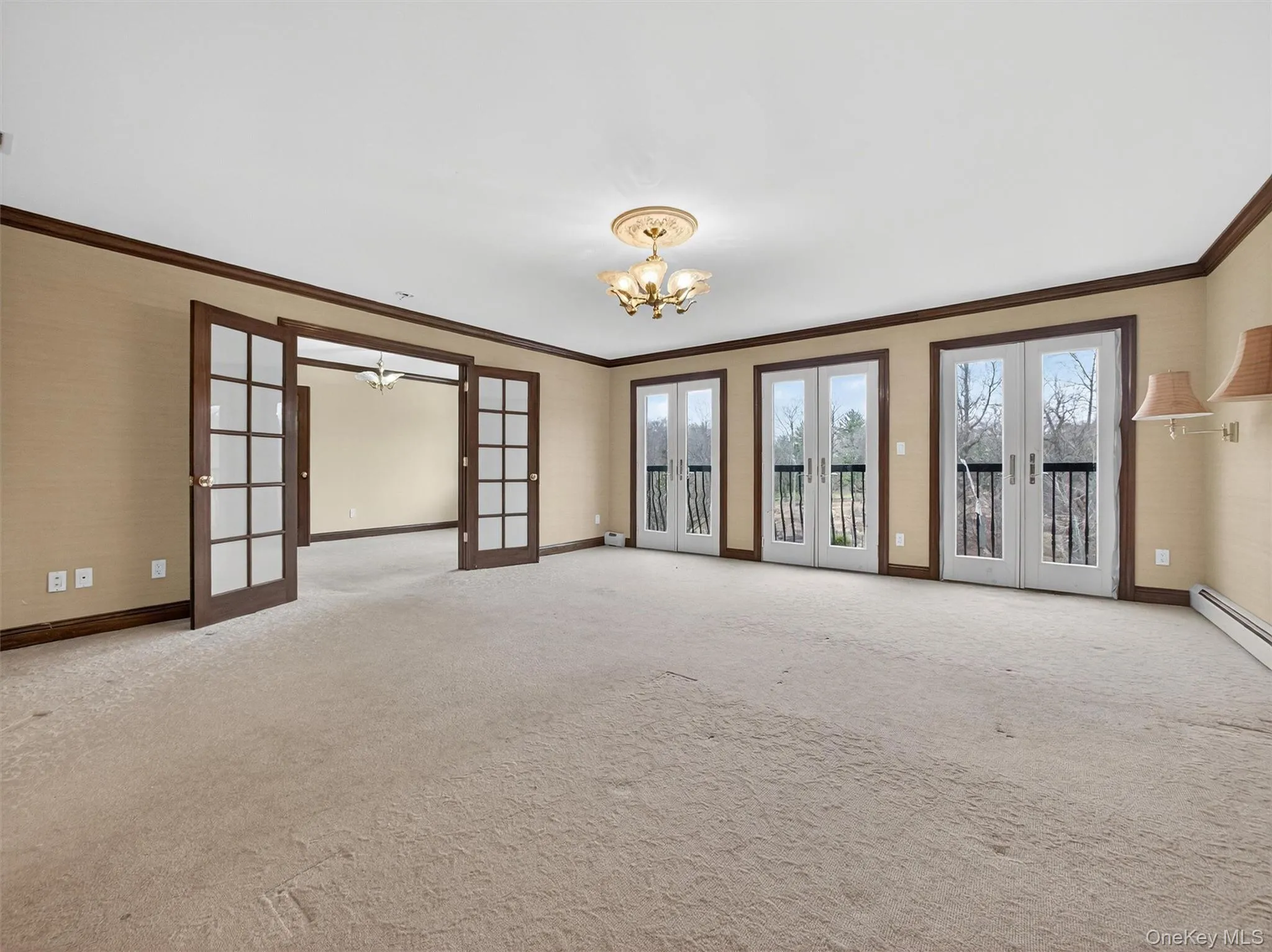 Spare room with french doors, ornamental molding, a chandelier, and light carpet Spare room with french doors, ornamental molding, a chandelier, and light carpet