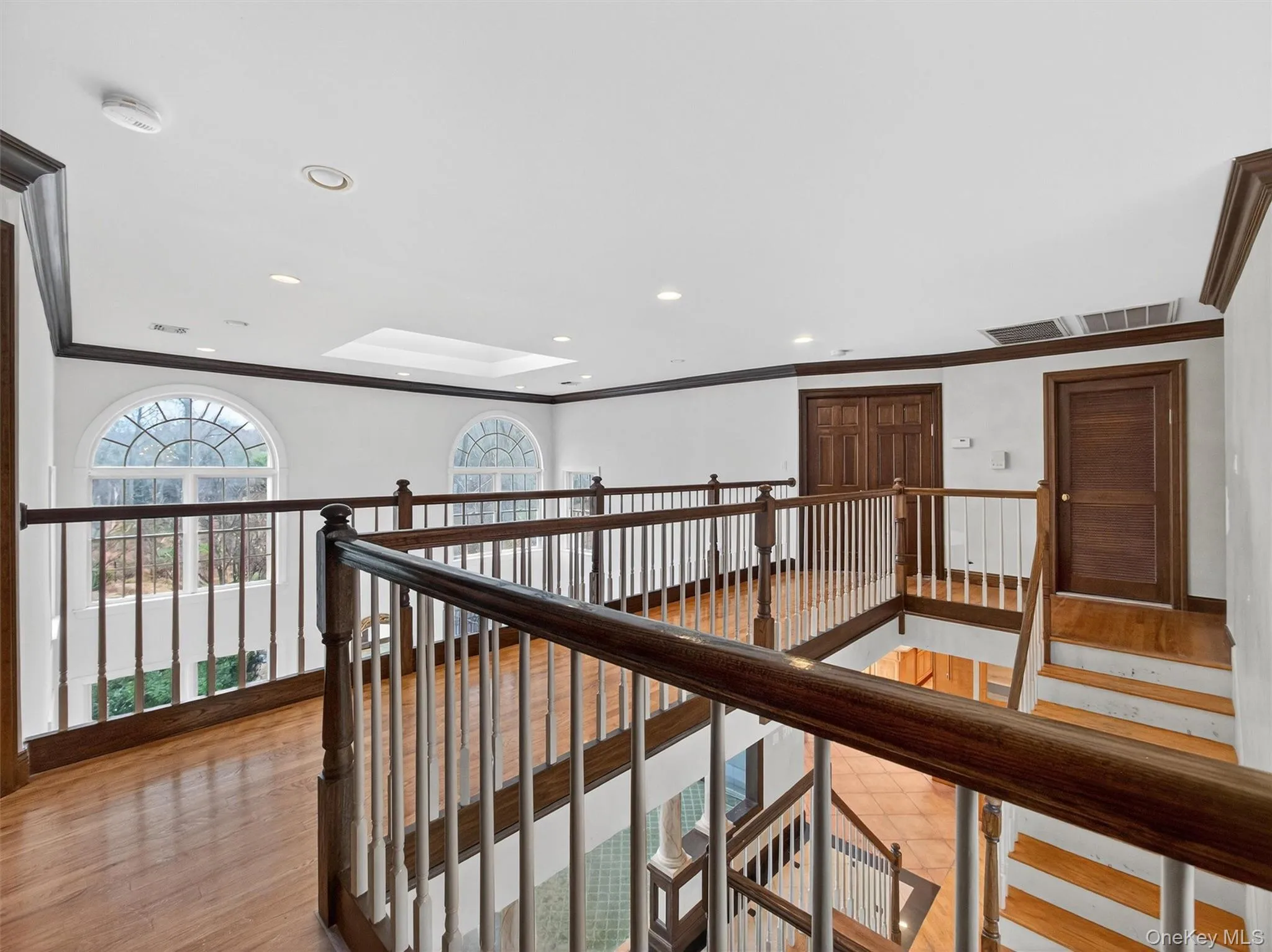 Hallway featuring crown molding, recessed lighting, light wood-style floors, an upstairs landing, and a skylight Hallway featuring crown molding, recessed lighting, light wood-style floors, an upstairs landing, and a skylight