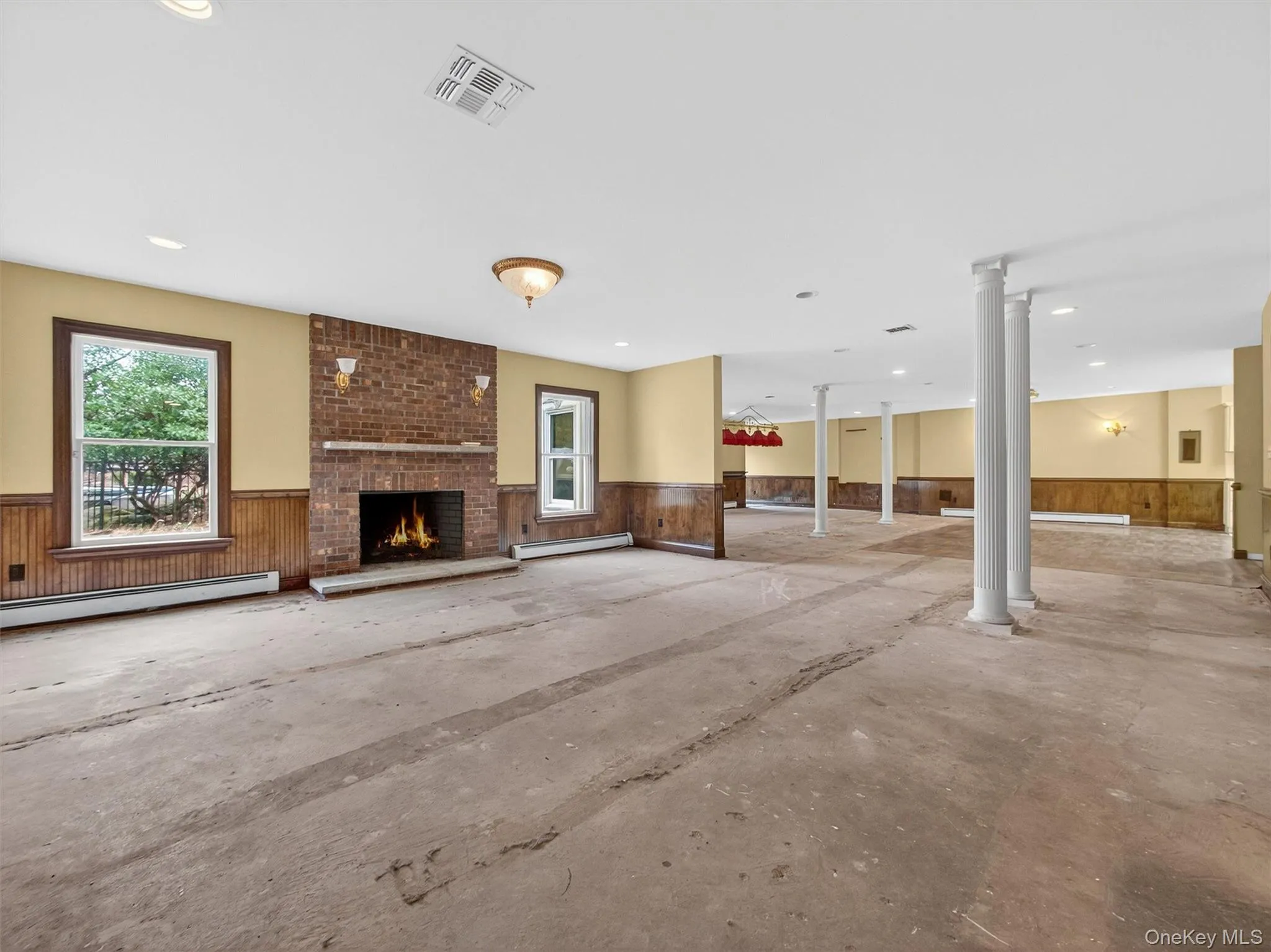 Unfurnished living room with a wainscoted wall, a fireplace, wood walls, a baseboard heating unit, and recessed lighting Unfurnished living room with a wainscoted wall, a fireplace, wood walls, a baseboard heating unit, and recessed lighting