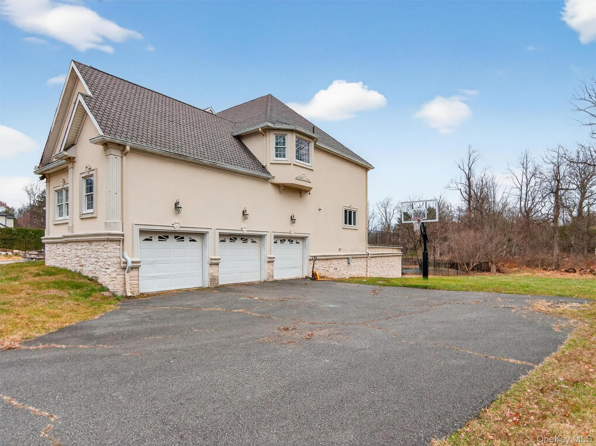View of property exterior with stucco siding, driveway, stone siding, and a lawn View of property exterior with stucco siding, driveway, stone siding, and a lawn
