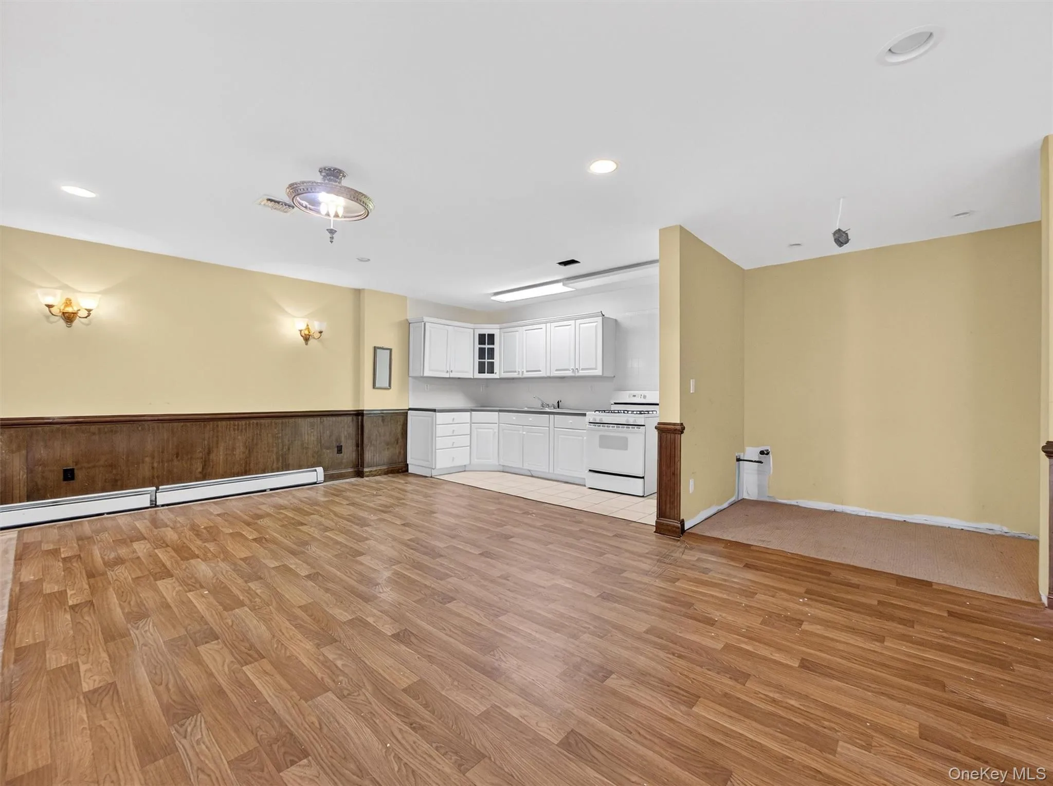 Kitchen featuring open floor plan, white cabinets, white gas range, light wood-type flooring, and recessed lighting Kitchen featuring open floor plan, white cabinets, white gas range, light wood-type flooring, and recessed lighting