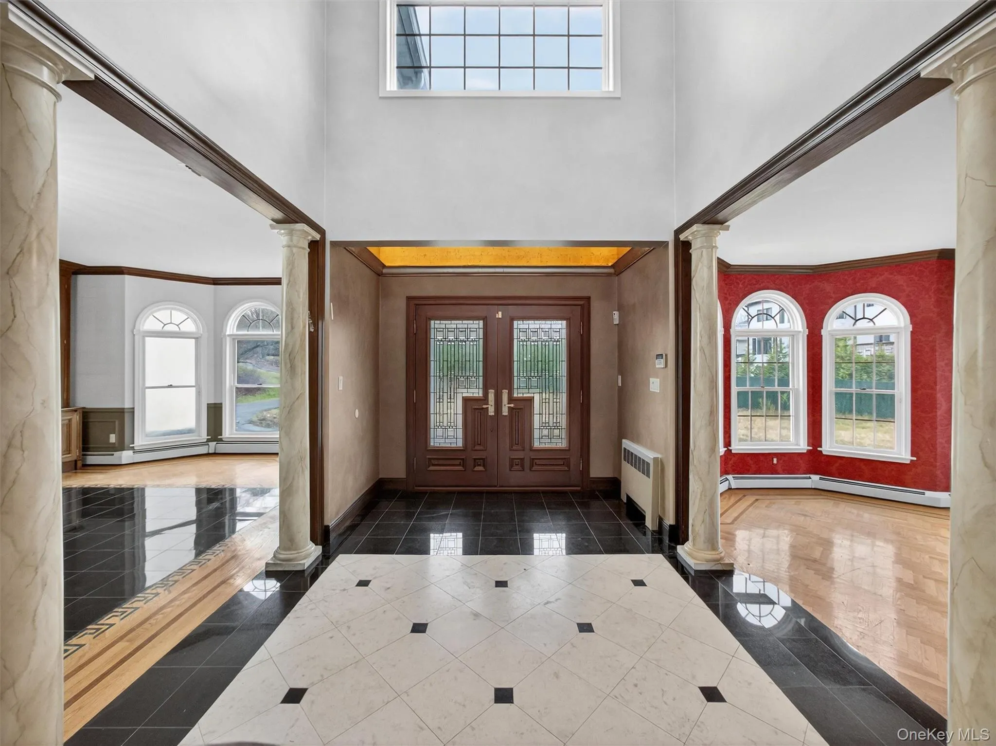 Entryway featuring crown molding, ornate columns, plenty of natural light, a high ceiling, and radiator heating unit Entryway featuring crown molding, ornate columns, plenty of natural light, a high ceiling, and radiator heating unit