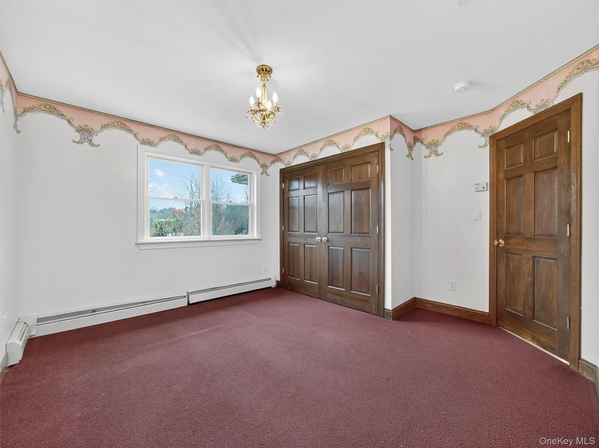 Unfurnished bedroom featuring carpet, a chandelier, a baseboard heating unit, and a closet Unfurnished bedroom featuring carpet, a chandelier, a baseboard heating unit, and a closet