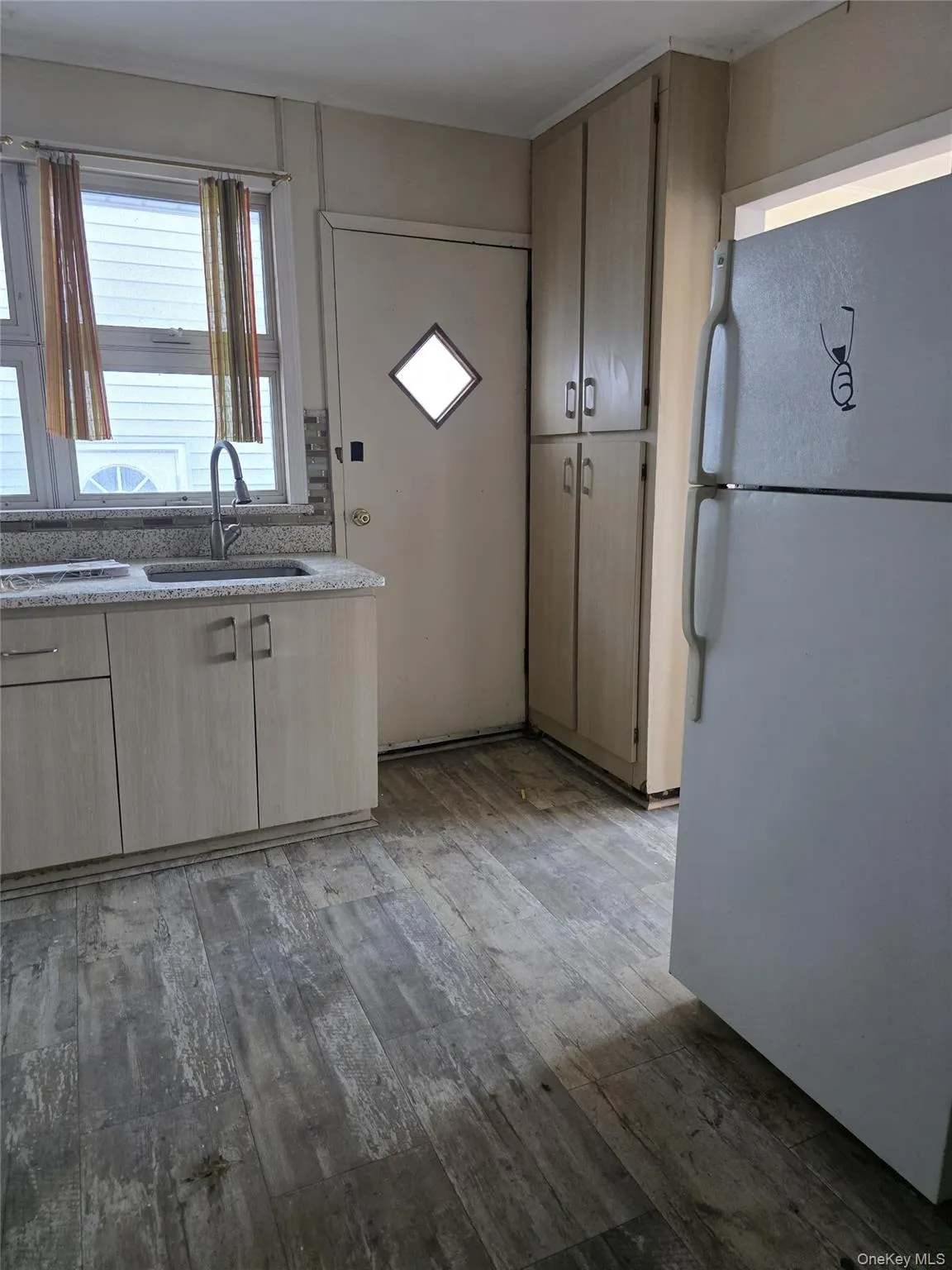 Kitchen featuring freestanding refrigerator, light wood finished floors, light brown cabinetry, and light stone counters Kitchen featuring freestanding refrigerator, light wood finished floors, light brown cabinetry, and light stone counters