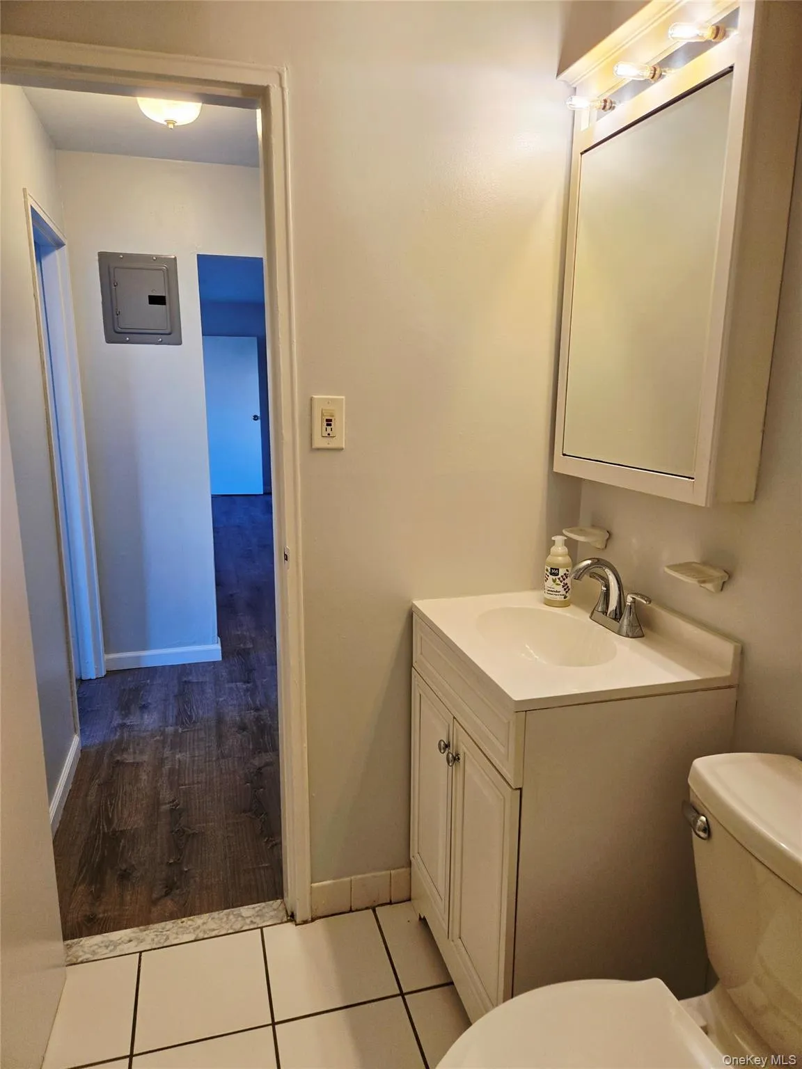 Half bath featuring electric panel, vanity, and light tile patterned floors Half bath featuring electric panel, vanity, and light tile patterned floors