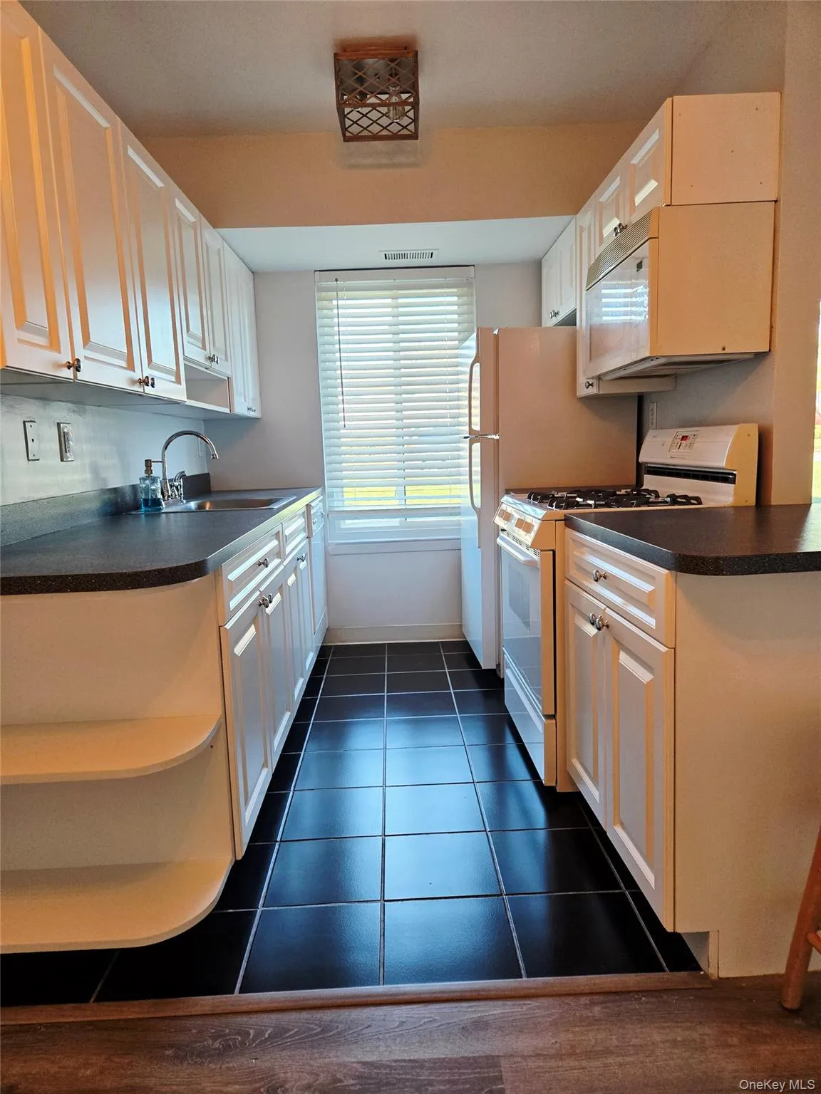 Kitchen featuring dark countertops, white appliances, open shelves, and dark tile patterned flooring Kitchen featuring dark countertops, white appliances, open shelves, and dark tile patterned flooring