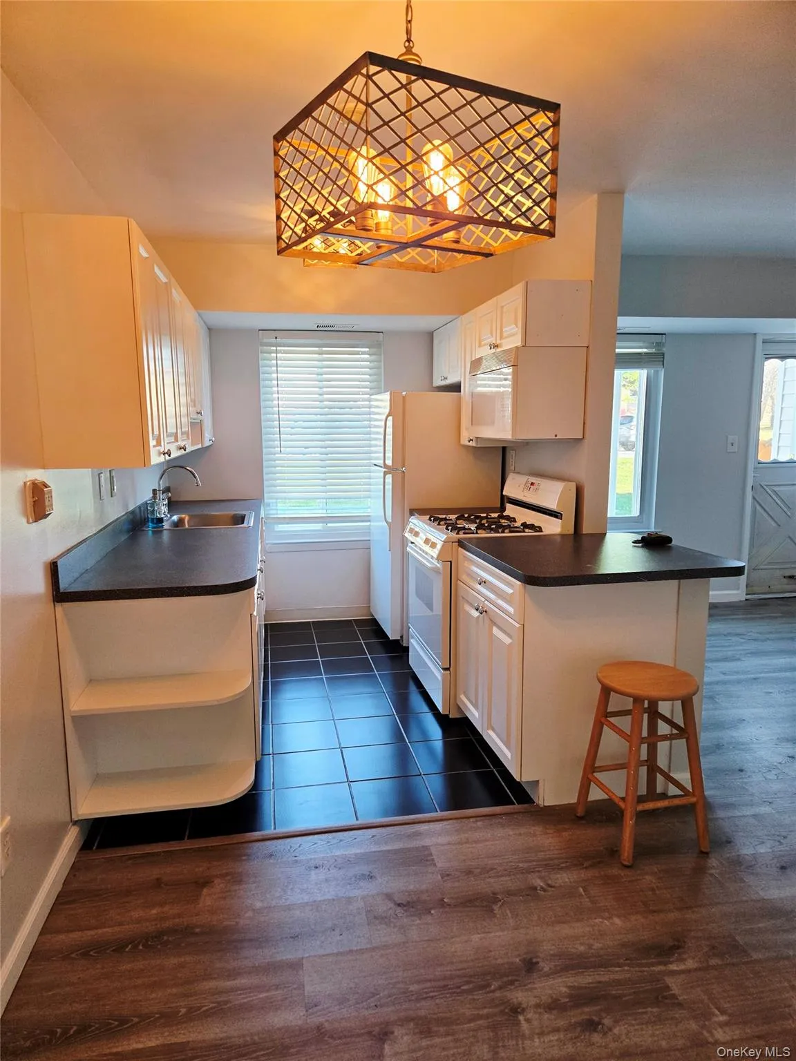 Kitchen with dark countertops, white appliances, healthy amount of natural light, and a peninsula Kitchen with dark countertops, white appliances, healthy amount of natural light, and a peninsula