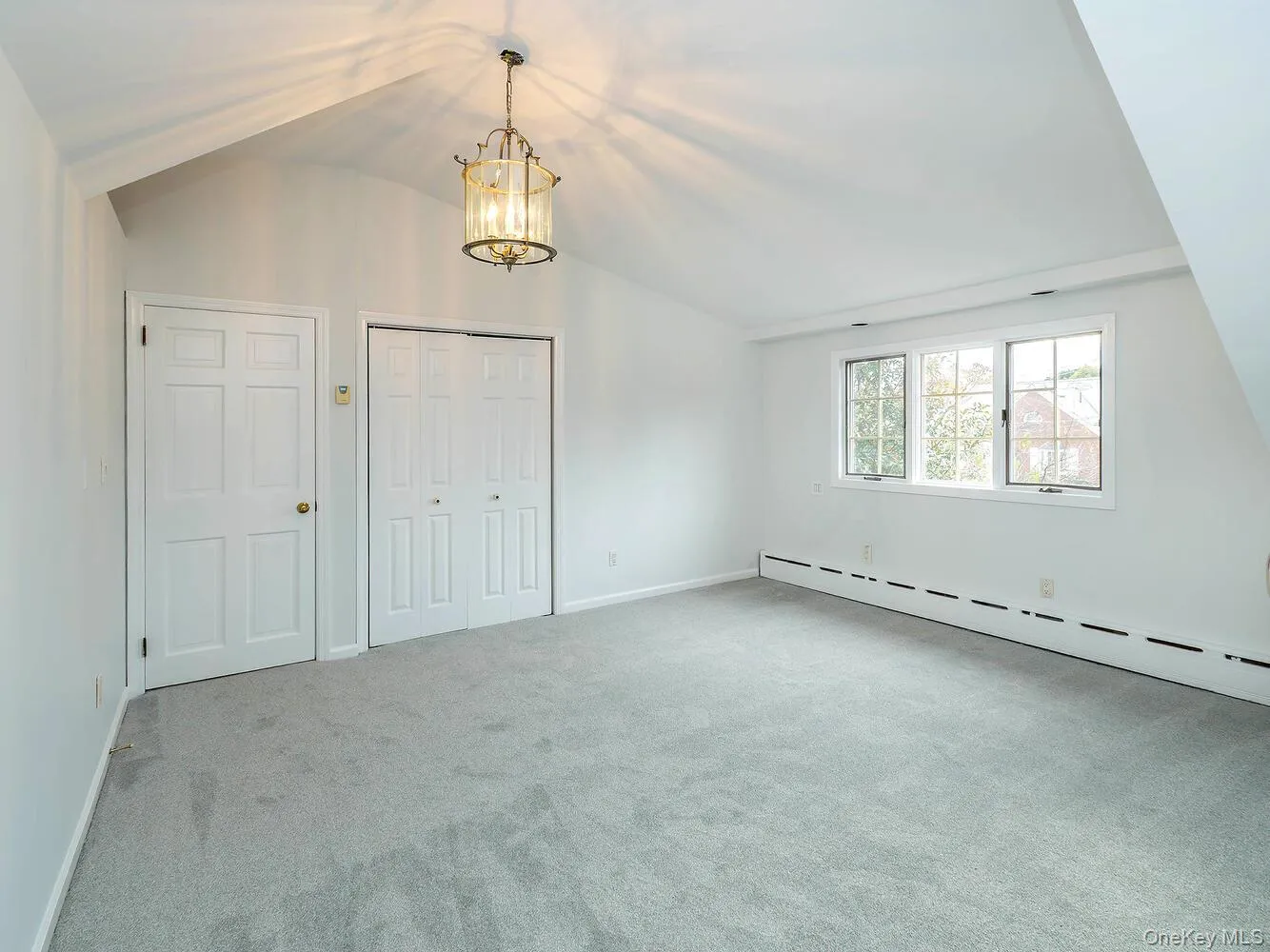 Unfurnished bedroom featuring vaulted ceiling, light colored carpet, a chandelier, and a closet Unfurnished bedroom featuring vaulted ceiling, light colored carpet, a chandelier, and a closet