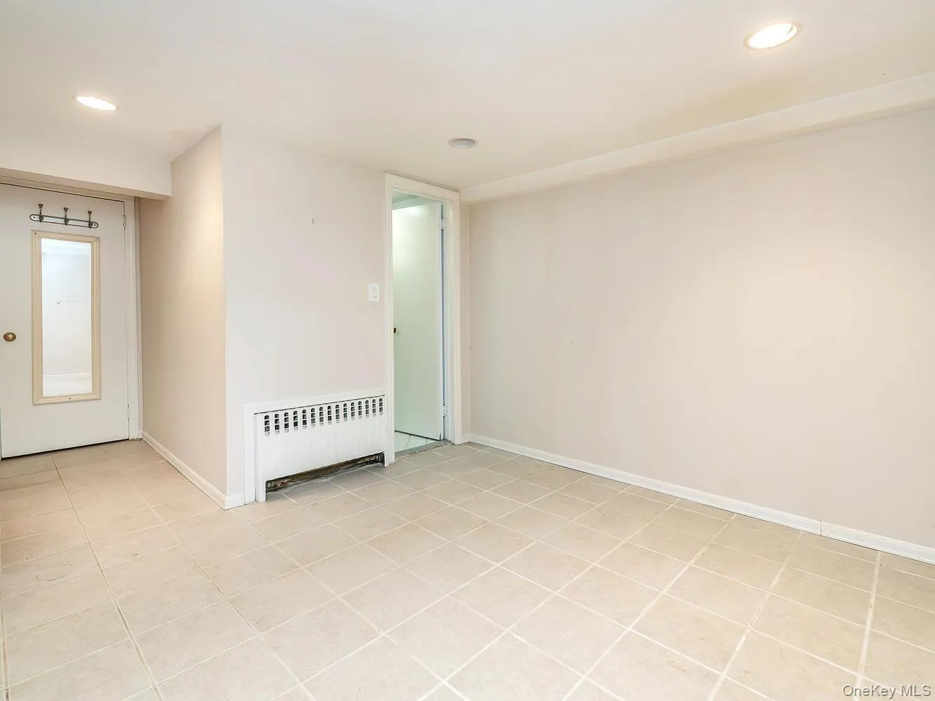 Unfurnished room featuring radiator, recessed lighting, and light tile patterned floors Unfurnished room featuring radiator, recessed lighting, and light tile patterned floors