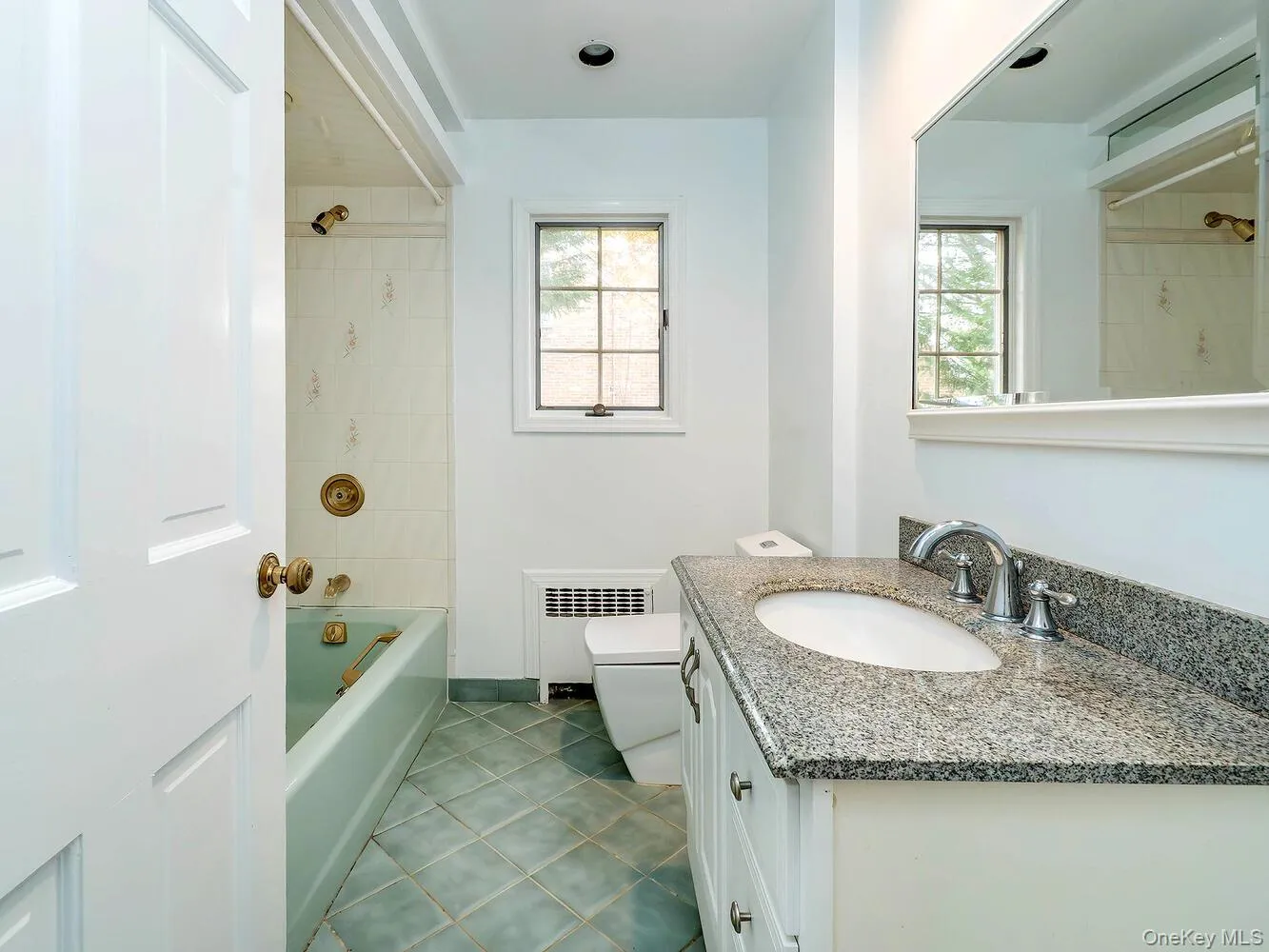 Bathroom with shower / tub combination, vanity, radiator, dark tile patterned floors, and plenty of natural light Bathroom with shower / tub combination, vanity, radiator, dark tile patterned floors, and plenty of natural light