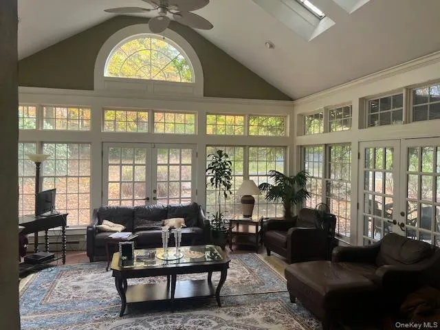 Sunroom with french doors, vaulted ceiling, a skylight, and a baseboard radiator Sunroom with french doors, vaulted ceiling, a skylight, and a baseboard radiator