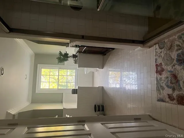 Full bath featuring a shower stall, crown molding, wainscoting, and light tile patterned floors Full bath featuring a shower stall, crown molding, wainscoting, and light tile patterned floors