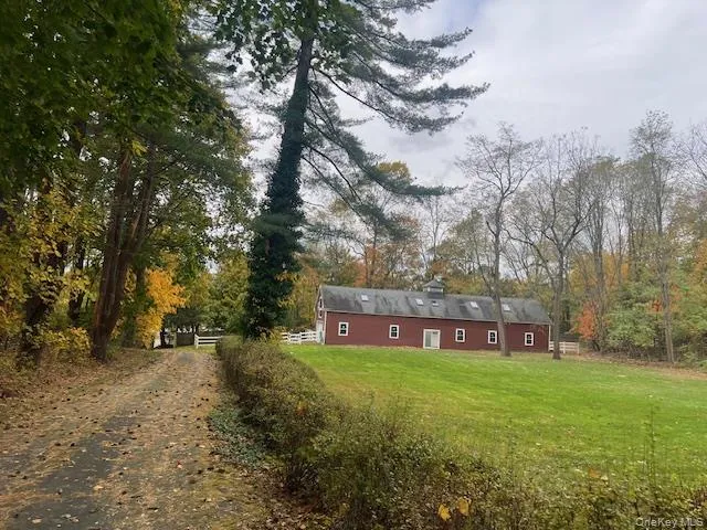 Back of house with a yard, a chimney, and a view of trees Back of house with a yard, a chimney, and a view of trees