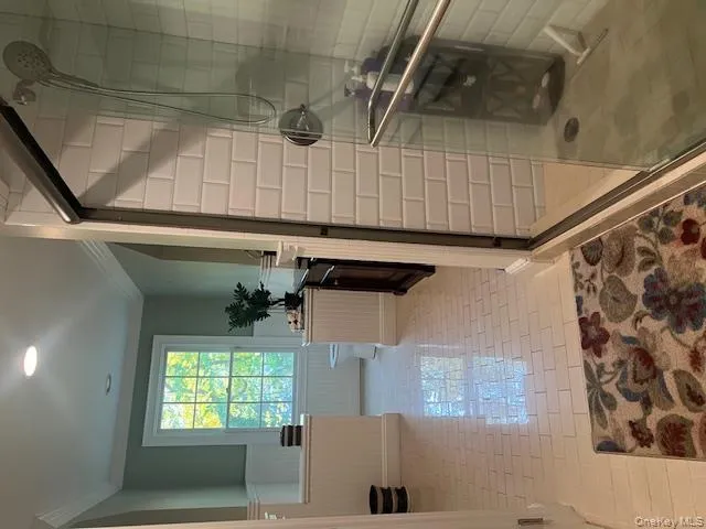 Bathroom with a wainscoted wall, crown molding, a shower stall, light tile patterned floors, and recessed lighting Bathroom with a wainscoted wall, crown molding, a shower stall, light tile patterned floors, and recessed lighting