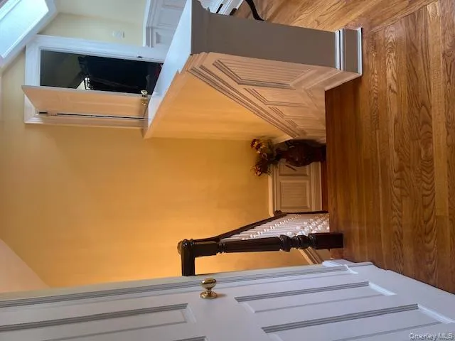 Stairway with wood finished floors, a decorative wall, a wainscoted wall, a skylight, and vaulted ceiling Stairway with wood finished floors, a decorative wall, a wainscoted wall, a skylight, and vaulted ceiling