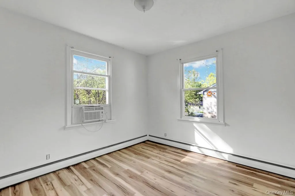 Spare room featuring light wood-style floors, a baseboard radiator, and cooling unit Spare room featuring light wood-style floors, a baseboard radiator, and cooling unit