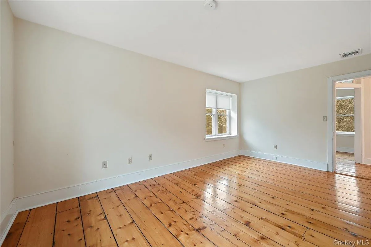Unfurnished room with wood-type flooring and baseboards Unfurnished room with wood-type flooring and baseboards