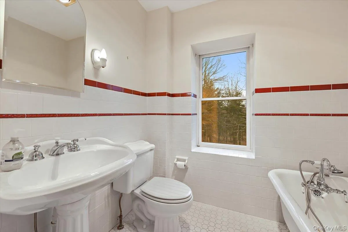 Full bathroom featuring tile walls, a freestanding bath, a wainscoted wall, and tile patterned floors Full bathroom featuring tile walls, a freestanding bath, a wainscoted wall, and tile patterned floors