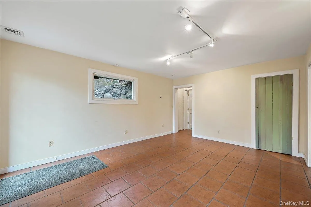 Tiled empty room with track lighting and baseboards Tiled empty room with track lighting and baseboards