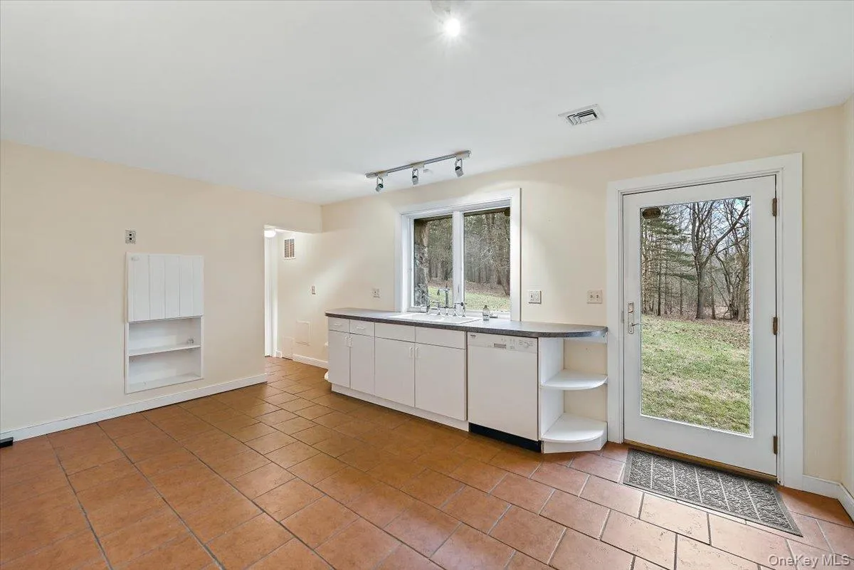 Kitchen with white cabinets, open shelves, plenty of natural light, and white dishwasher Kitchen with white cabinets, open shelves, plenty of natural light, and white dishwasher